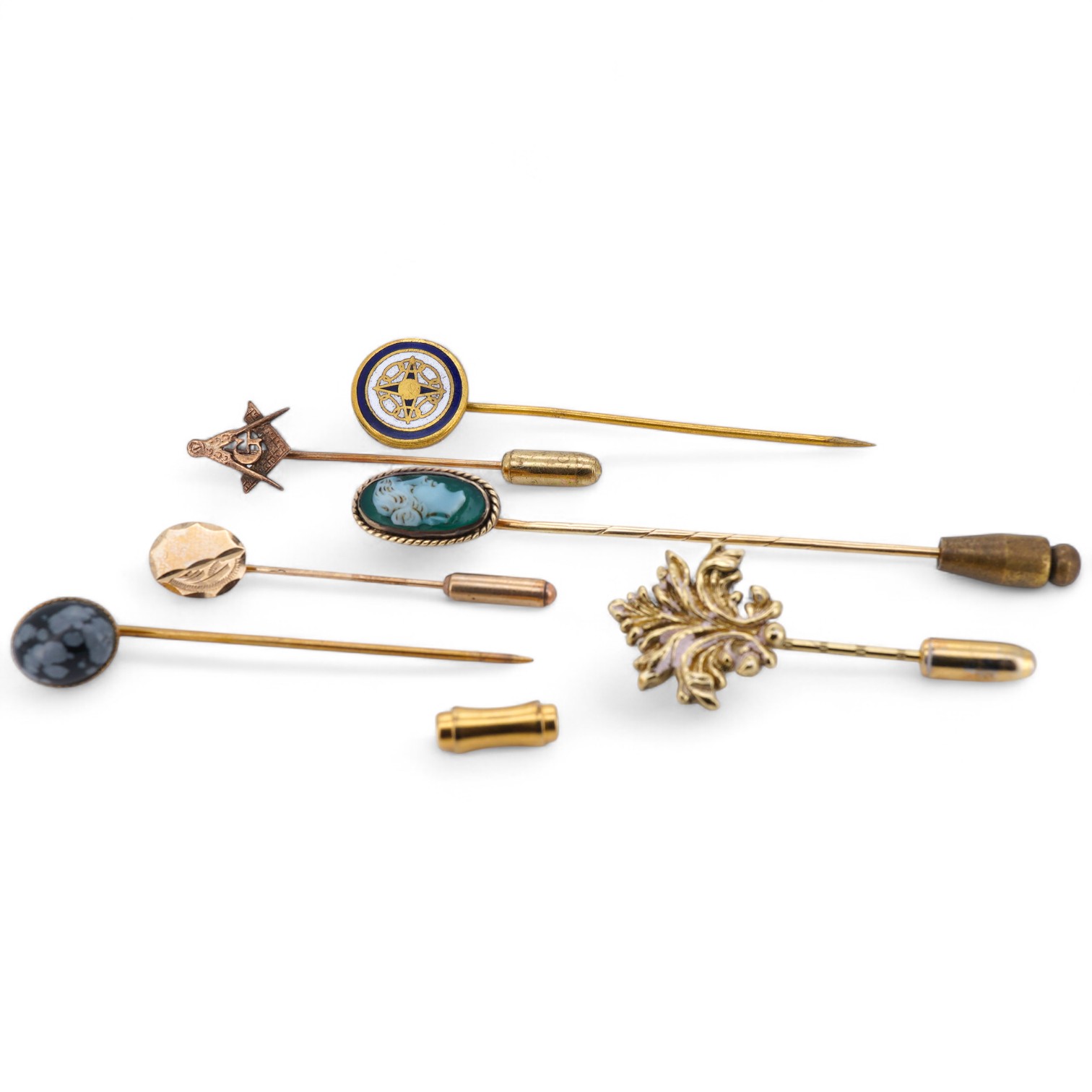 A collection of six stick pins, comprising: three gold stick pins, one set with a hardstone cameo, Austrian assay marks; a gold stick pin with a faceted edge; and a gold stick pin of Masonic design, stamped 9CT, combined